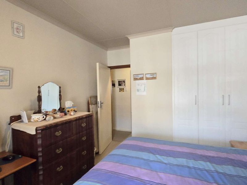 A functional bedroom featuring a built-in wardrobe and coved ceiling, offering a neutral base for potential interior updates.