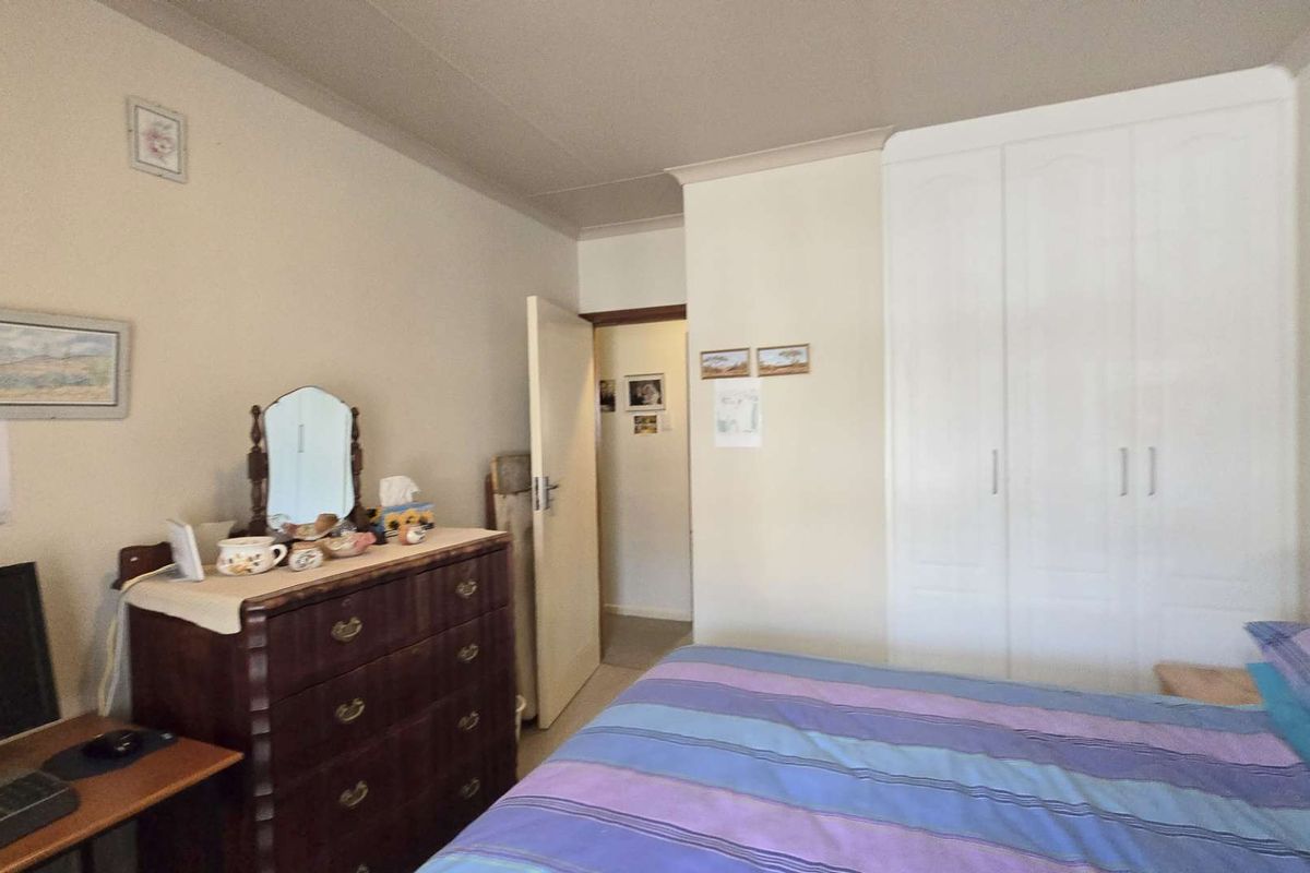 A functional bedroom featuring a built-in wardrobe and coved ceiling, offering a neutral base for potential interior updates.