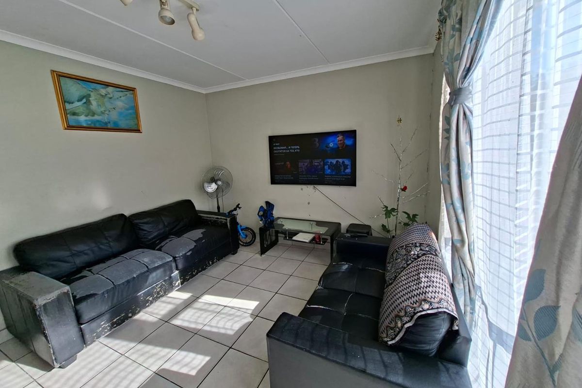 A living room featuring tiled flooring and track lighting, providing a functional space for relaxation.