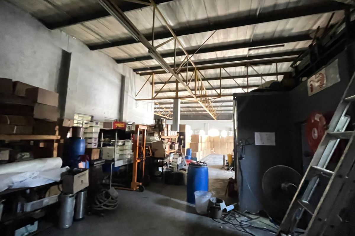 A functional industrial utility or storage space featuring exposed steel roof trusses, concrete flooring, and high ceilings suitable for commercial operations.