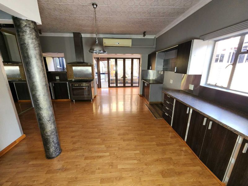 Spacious kitchen featuring dark cabinetry, laminate flooring, decorative ceiling tiles, and direct access to an outdoor patio area.