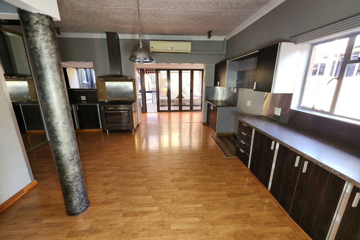 Spacious kitchen featuring dark cabinetry, laminate flooring, decorative ceiling tiles, and direct access to an outdoor patio area.