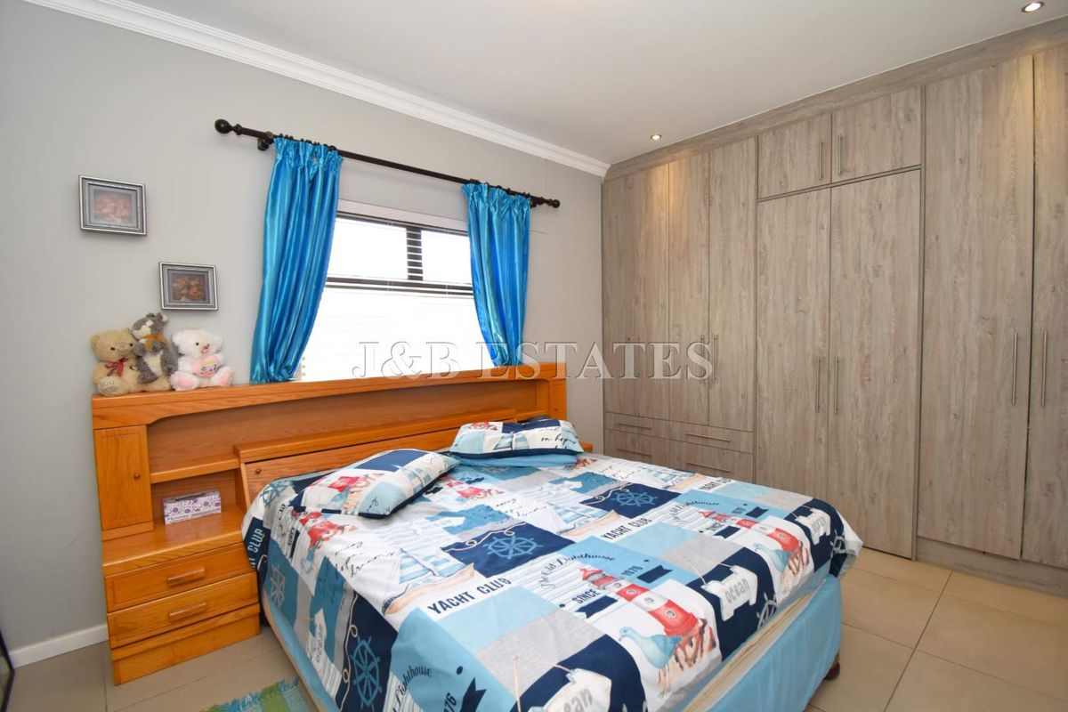 A well-maintained bedroom featuring built-in wooden cabinetry and tiled flooring, offering ample storage space and a neutral color palette.