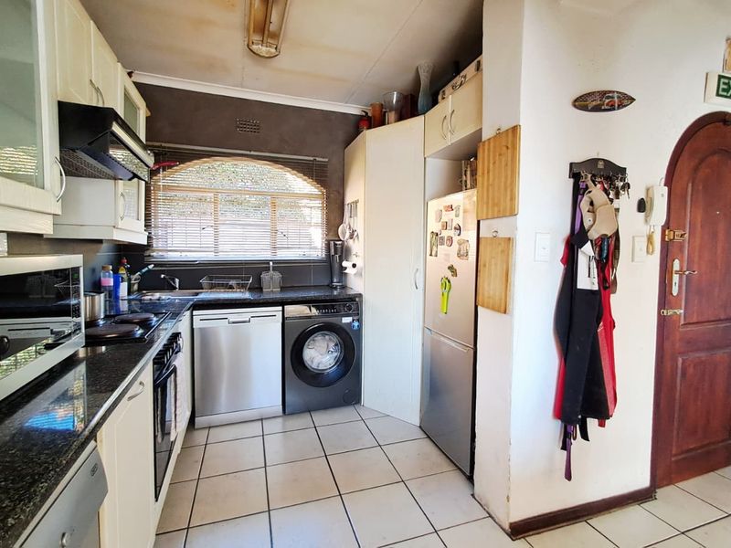 Compact kitchen featuring granite countertops, built-in cabinetry, and tiled flooring. The space requires ceiling repairs and cosmetic updates to improve its overall condition.