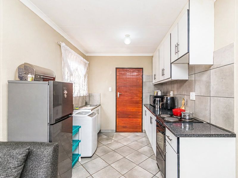 A functional kitchen featuring white cabinetry, granite countertops, tiled backsplash, and tiled flooring, providing a practical workspace with integrated cooking appliances.