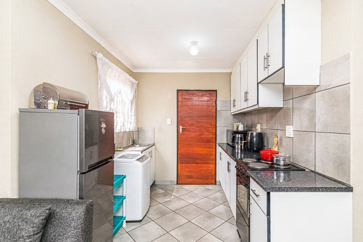 A functional kitchen featuring white cabinetry, granite countertops, tiled backsplash, and tiled flooring, providing a practical workspace with integrated cooking appliances.