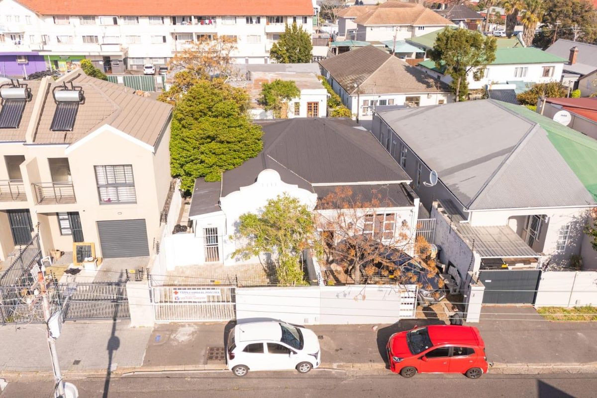 Aerial view of the property showing the roof structure, perimeter wall, and driveway access from the street.
