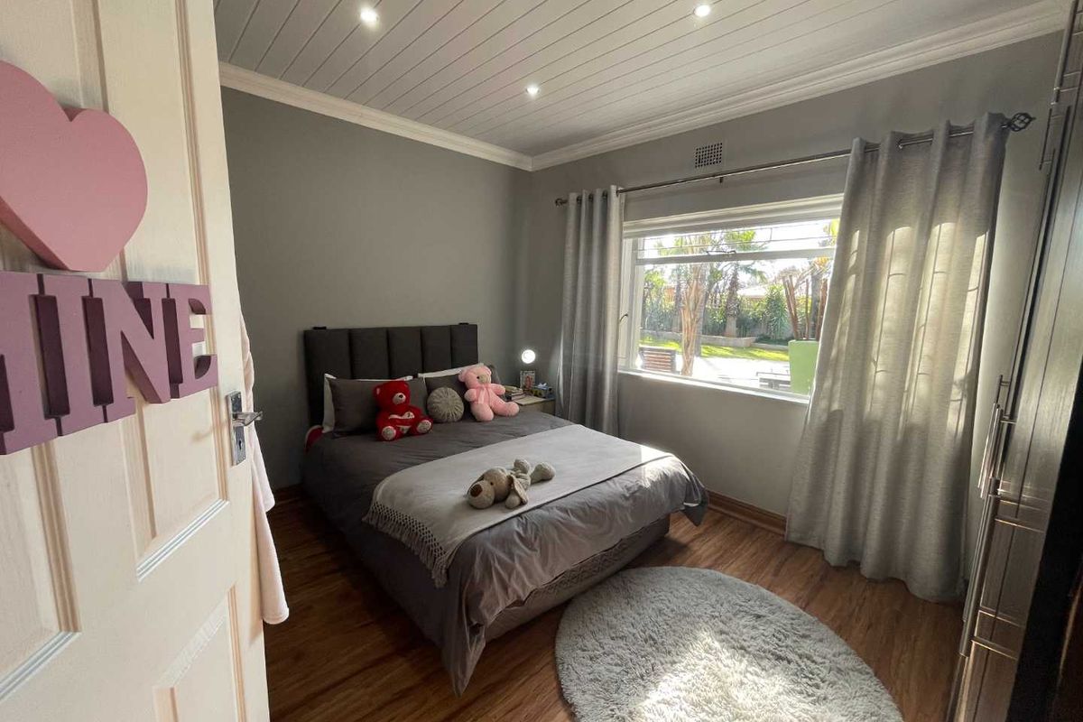 A well-maintained bedroom featuring laminate flooring, a tongue and groove ceiling with recessed lighting, and built-in wardrobe storage.