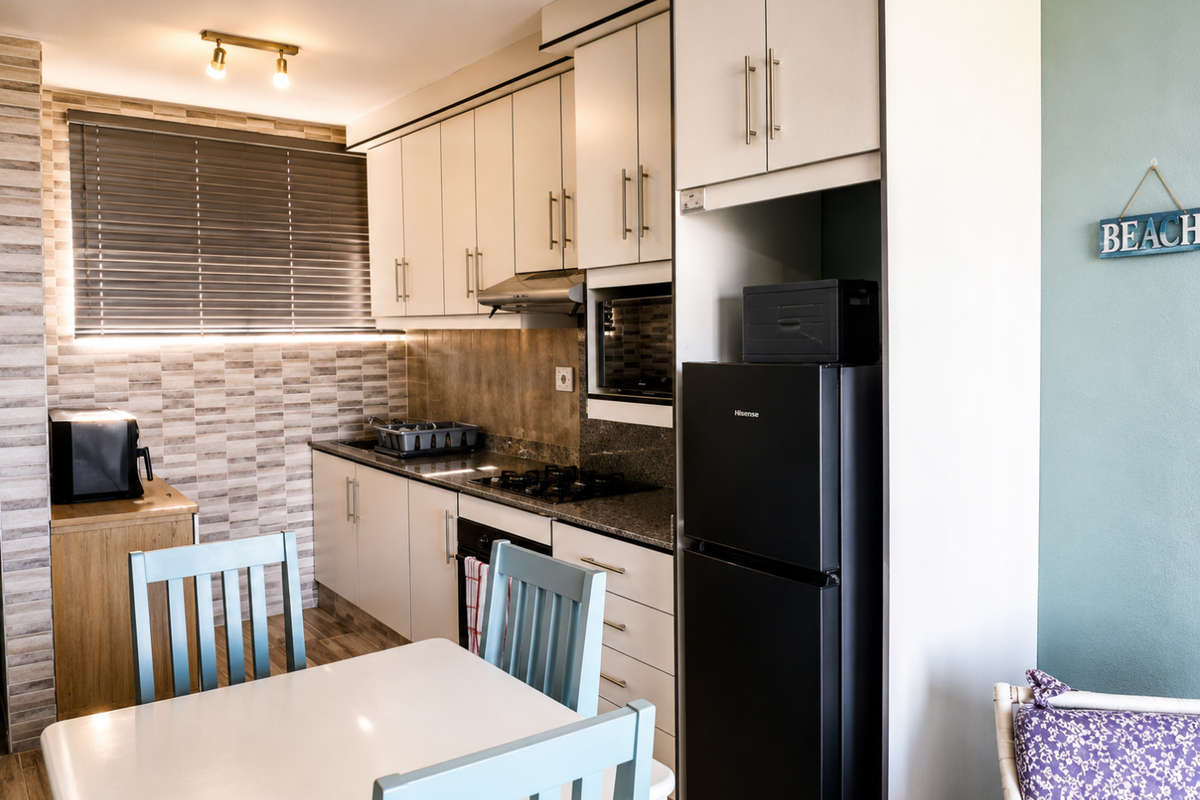 A compact, well-maintained kitchen featuring modern cabinetry, granite countertops, a gas hob, and an integrated oven, complemented by a tiled backsplash and venetian blinds.