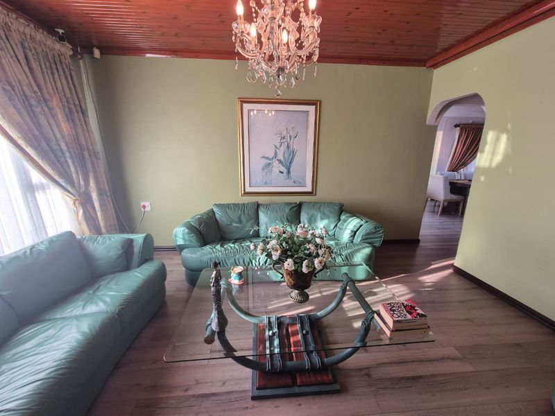 A living room featuring a timber-paneled ceiling, laminate flooring, and an arched entryway leading to an adjacent space.