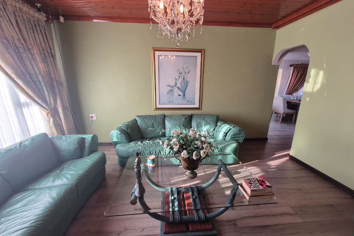 A living room featuring a timber-paneled ceiling, laminate flooring, and an arched entryway leading to an adjacent space.
