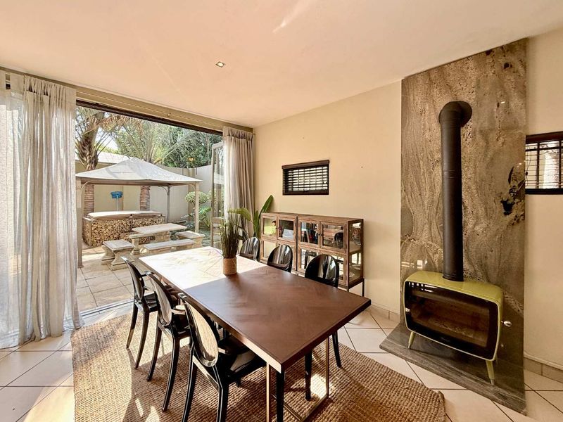 Dining area featuring a stylish stone-surround fireplace and large sliding glass doors that open onto a private patio and garden space.