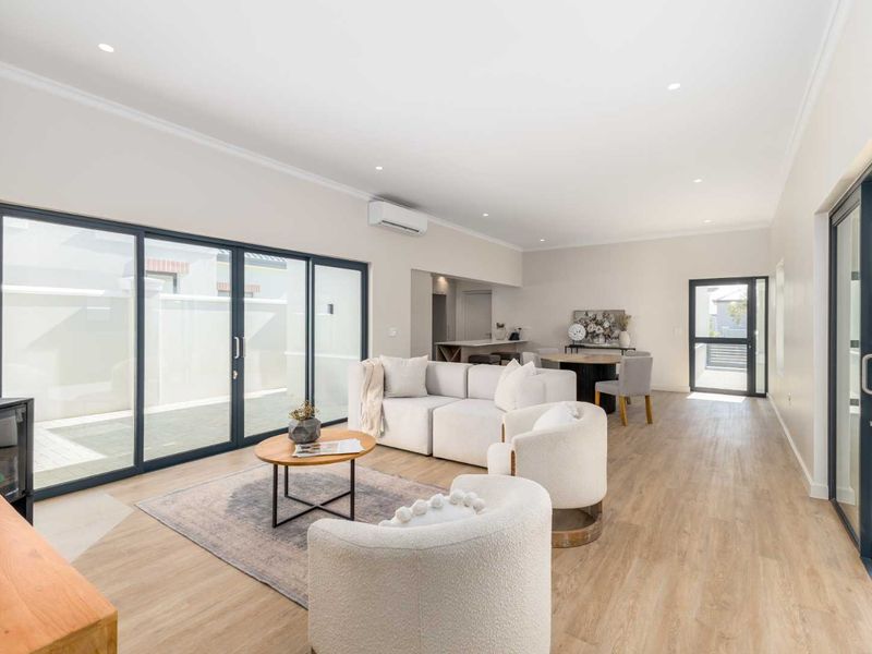 Spacious open-plan living area featuring modern laminate flooring, recessed lighting, a fireplace, and large sliding glass doors providing seamless access to the outdoor space.