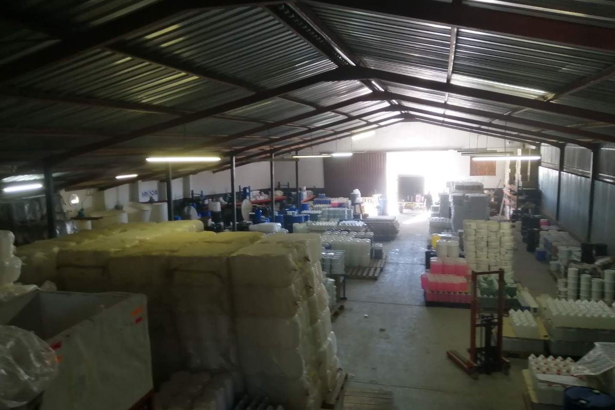Spacious industrial warehouse featuring high-clearance corrugated metal roofing, exposed steel trusses, concrete flooring, and a large roller door for loading access.