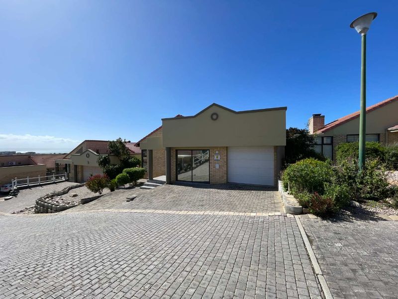 Front view of a residential property featuring a paved driveway, single garage, and brick facade in a well-maintained estate setting.