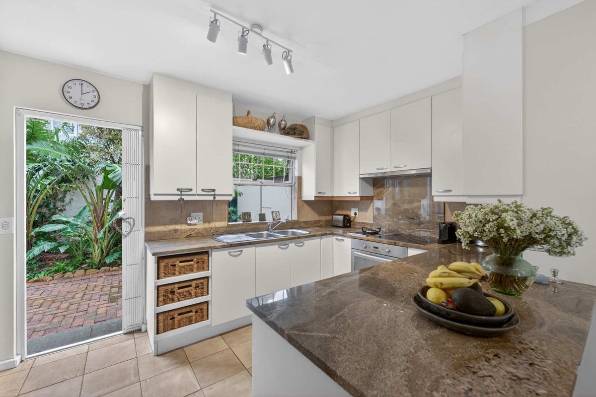 A well-maintained kitchen featuring stone countertops, built-in cabinetry, integrated appliances, and direct access to a private outdoor patio area.