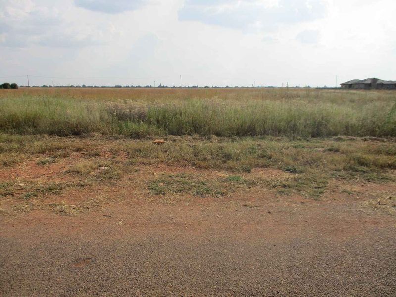A view of a vacant residential plot of land featuring natural grassland and open space.
