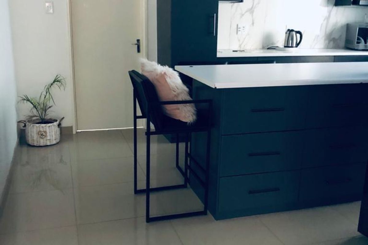 Modern kitchen featuring a dark-toned island, stone countertops, marble-look splashback, and open shelving, complemented by sleek tiled flooring.