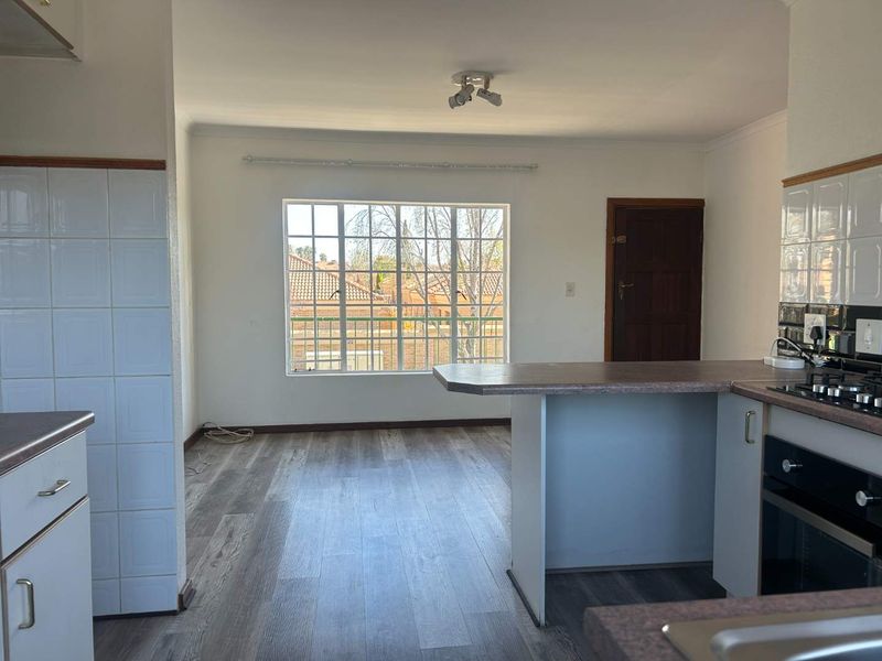 Open plan kitchen and living area featuring laminate flooring, built-in oven, gas hob, and a breakfast bar, offering a functional and bright living space.