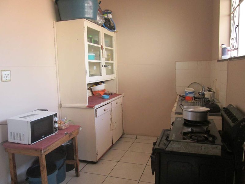 A functional kitchen space featuring built-in cabinetry, tiled flooring, and a tiled splashback, offering potential for modernization and renovation.