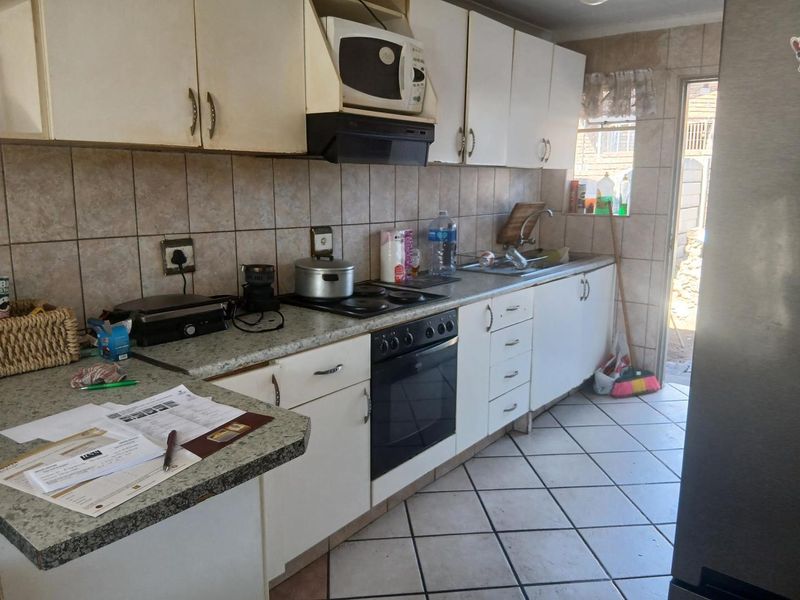 A functional kitchen featuring built-in cabinetry, laminate countertops, a built-in oven with hob, and ceramic tile flooring with direct access to the exterior.