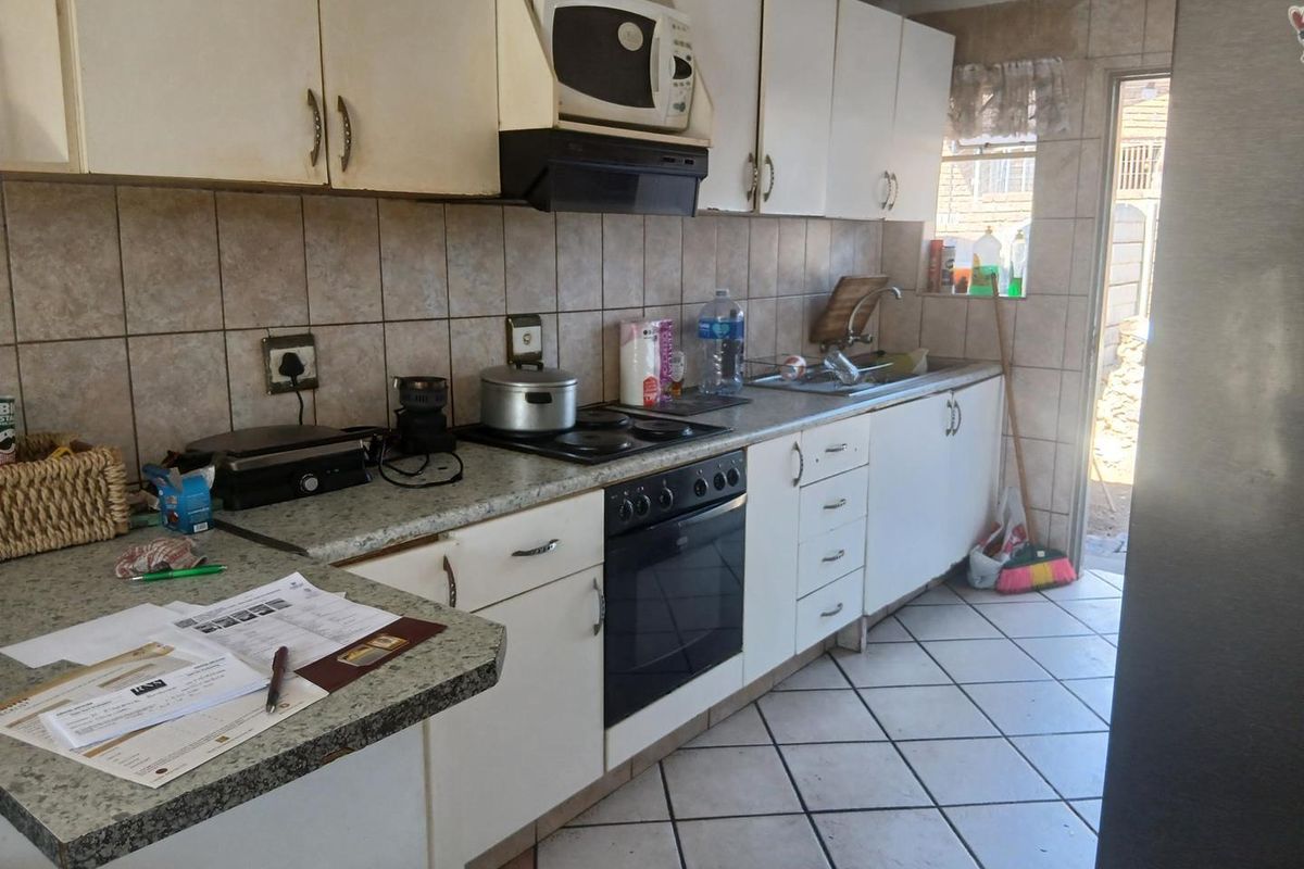 A functional kitchen featuring built-in cabinetry, laminate countertops, a built-in oven with hob, and ceramic tile flooring with direct access to the exterior.