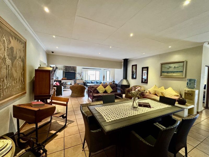 Spacious open-plan living and dining area featuring tiled flooring, recessed lighting, and a prominent freestanding fireplace, creating a versatile and connected family space.