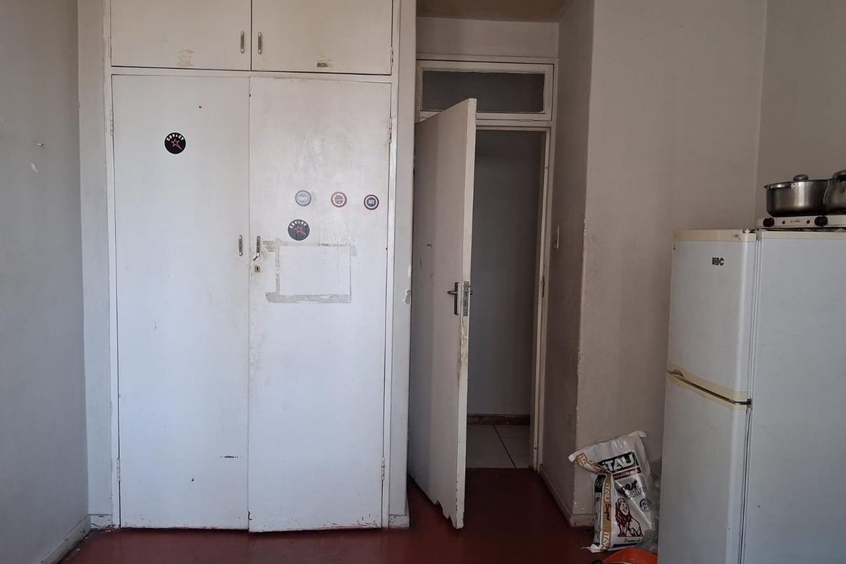A bedroom featuring built-in cupboards and an internal door, showing significant signs of wear and requiring cosmetic updates to improve the living space.