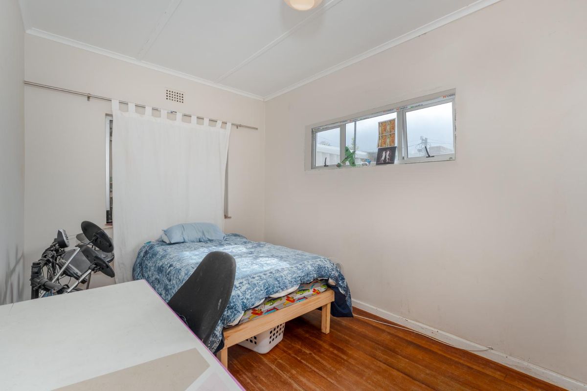 A functional bedroom featuring timber flooring and a sliding window, providing a neutral space ready for personalization.