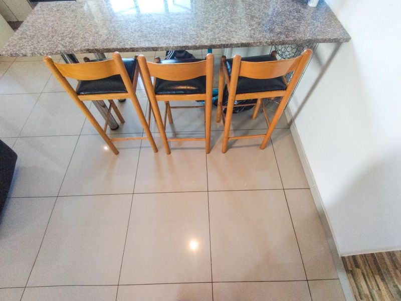 A kitchen area featuring a granite breakfast bar counter and neutral ceramic floor tiling.