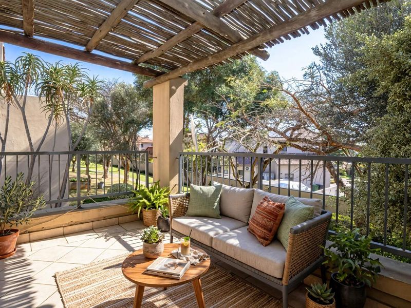 A well-maintained balcony featuring a timber pergola, metal safety railing, and tiled flooring, offering a pleasant outdoor space with views of the surrounding greenery.