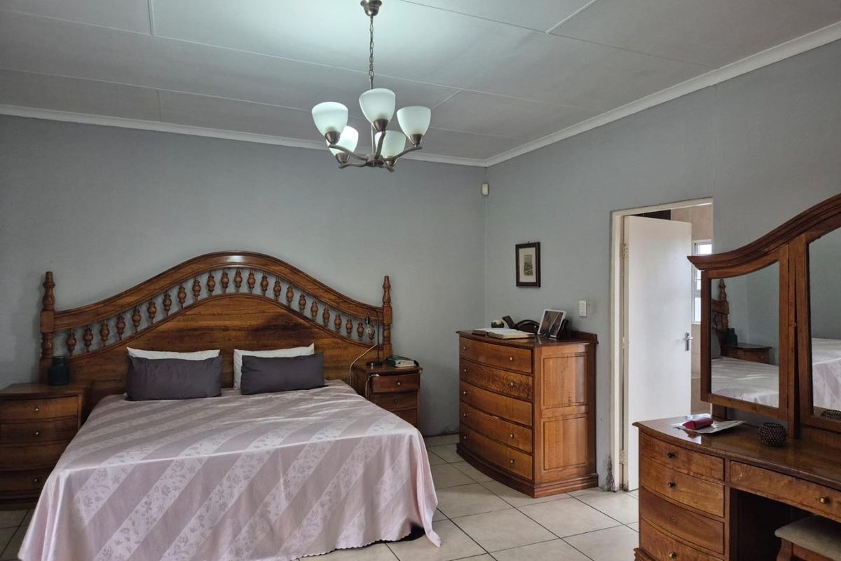 A spacious bedroom featuring tiled flooring and a central ceiling light fixture, providing a functional and well-maintained living space.