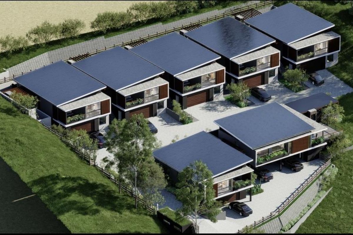 An aerial view of a modern residential housing complex featuring multiple units with solar panels, private garages, and landscaped surroundings.