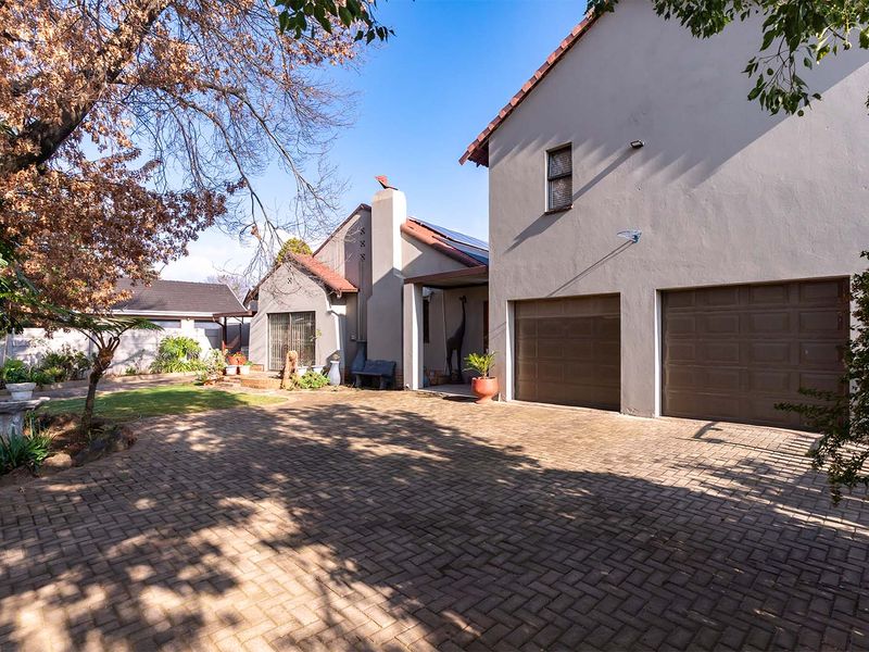 A view of the property's exterior featuring a paved driveway, double garage, and a landscaped garden area.