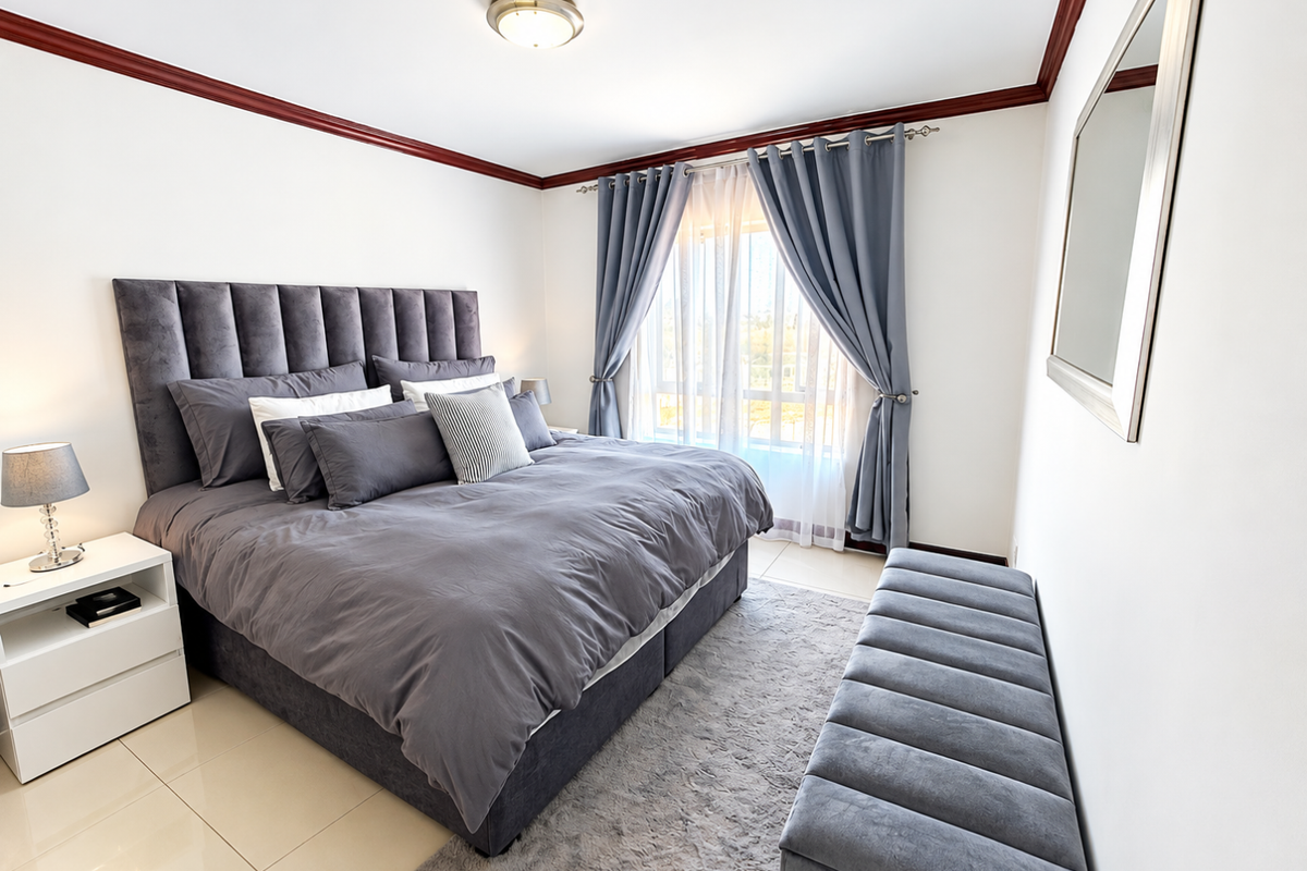 A well-maintained bedroom featuring tiled flooring, crown molding, and a large window with curtains, providing a bright and comfortable living space.