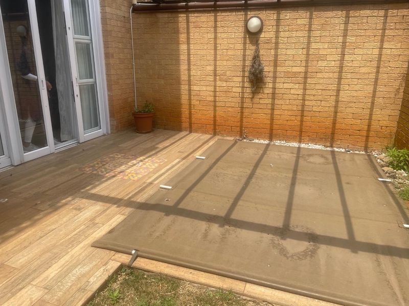 A paved patio area featuring a pergola structure, brick walling, and direct access to the interior via sliding glass doors.