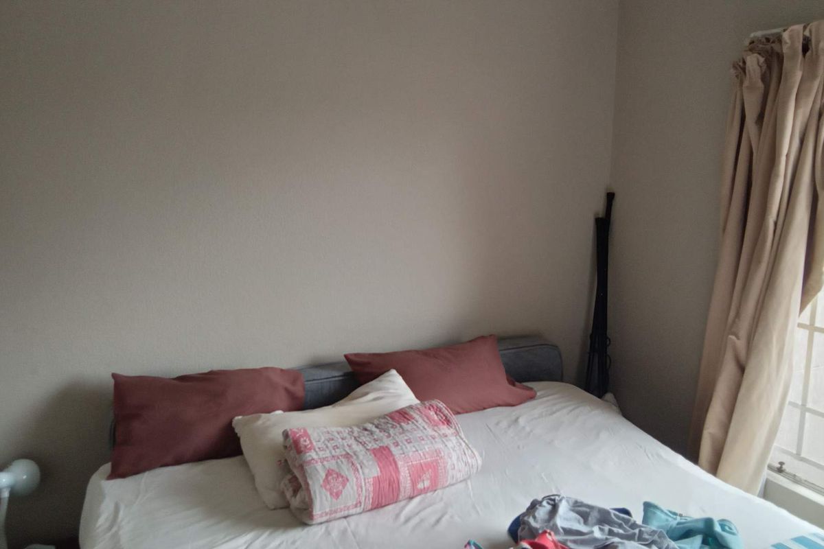 A bedroom featuring a window with fitted curtains and neutral wall finishes.