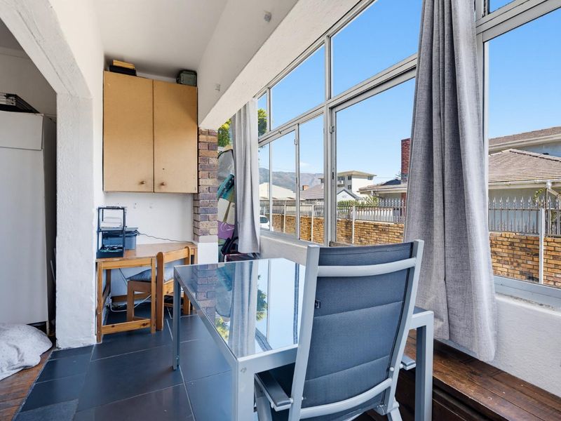 Enclosed balcony or sunroom featuring large windows, tiled flooring, and built-in storage cabinetry, offering a bright and versatile space.