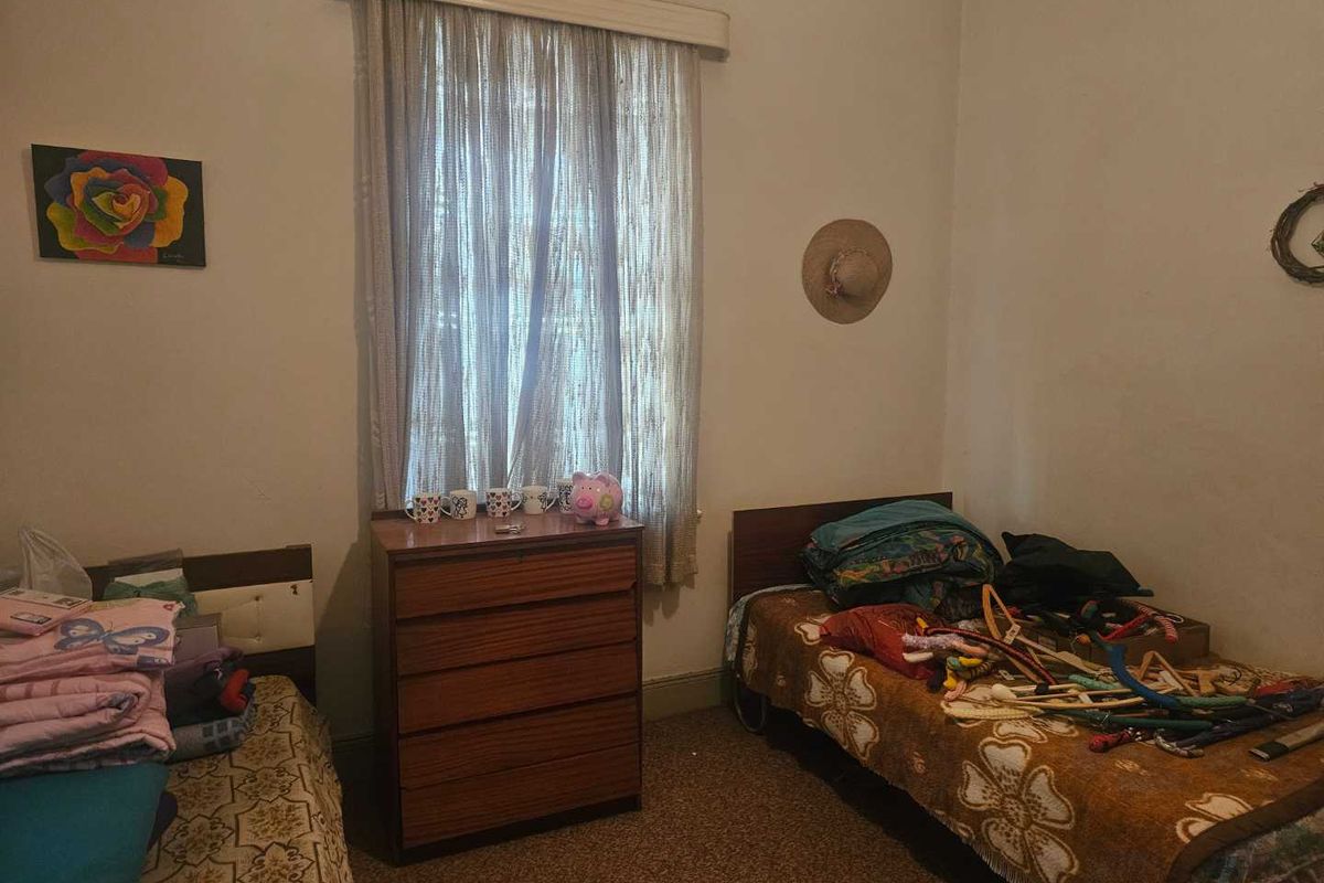 A bedroom featuring carpet flooring and a window with curtains, providing a functional space for sleeping.