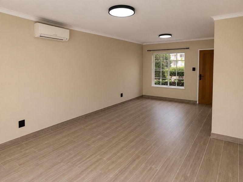 A bright, empty living room featuring modern tiled flooring, a split-system air conditioner, and neutral wall finishes, ready for personalization.