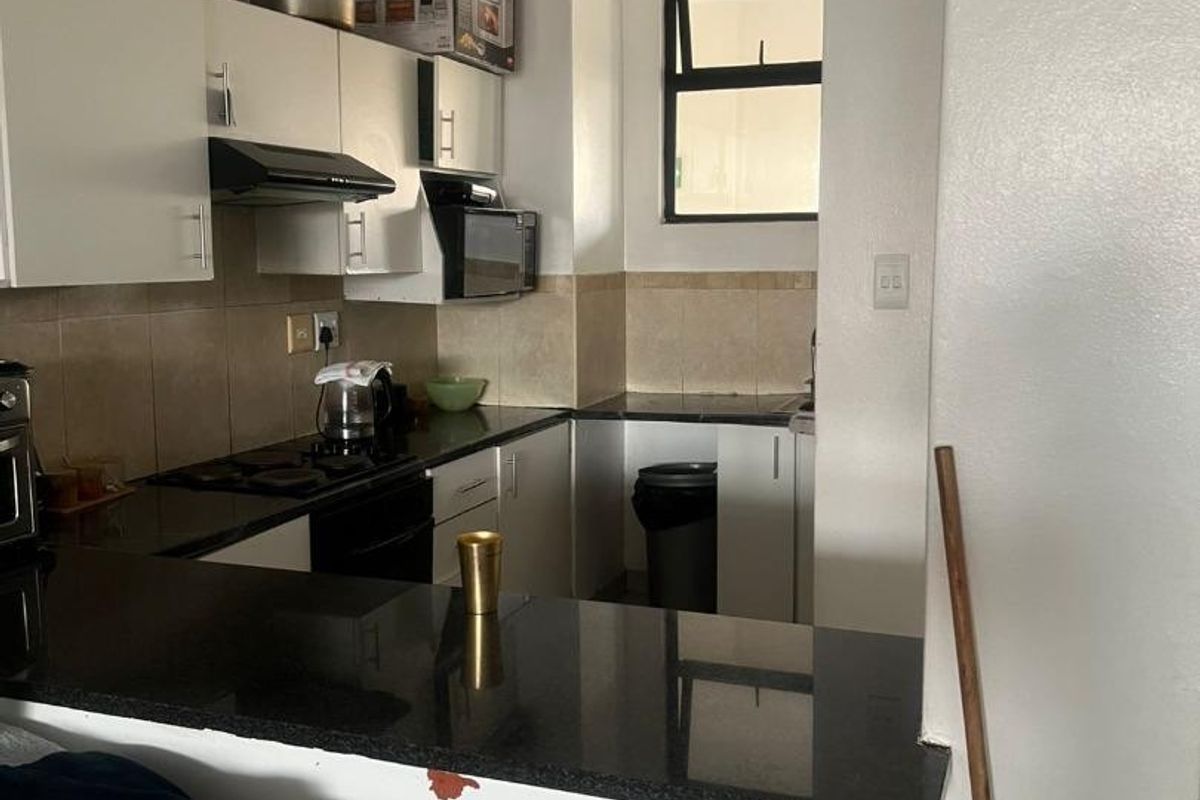 Compact kitchen featuring granite countertops, built-in cabinetry, a breakfast bar, and integrated appliances, offering a functional layout for daily cooking and dining.