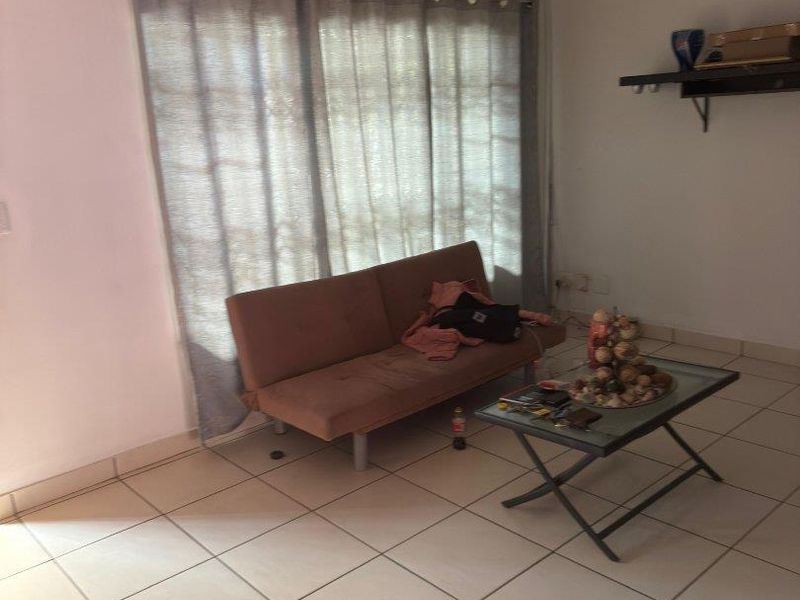 A living room area featuring ceramic floor tiles, a sliding glass door for natural light, and a wall-mounted shelf.