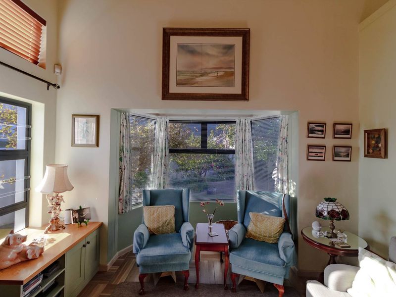 A cozy living room featuring a prominent bay window, built-in cabinetry, and warm timber flooring, creating a bright and inviting atmosphere.