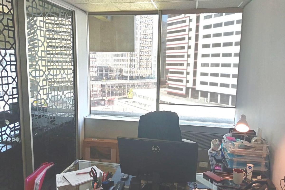 A functional office space featuring a decorative metal partition, large windows with city views, and a suspended ceiling.