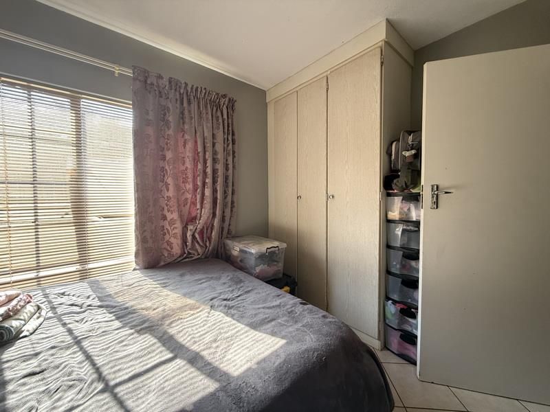 A bedroom featuring built-in cupboards and tiled flooring, providing functional storage space.