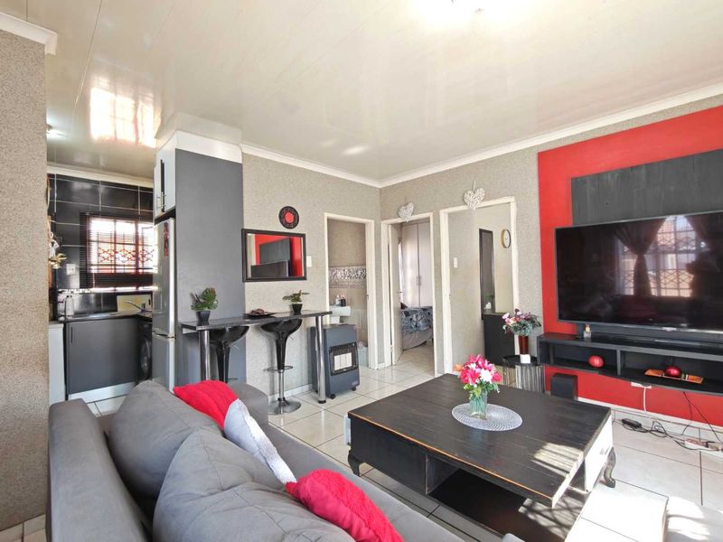Open-plan living area featuring a breakfast bar, tiled flooring, and an integrated kitchen space with modern cabinetry.
