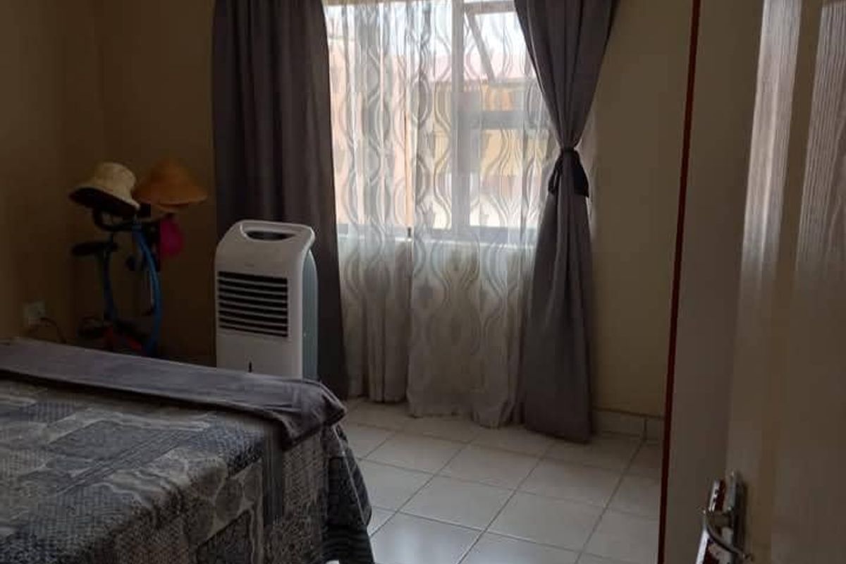 A bedroom featuring tiled flooring and a window with curtain treatments, providing a functional living space.