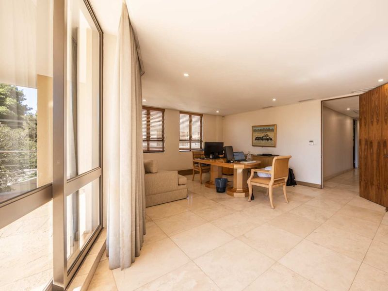 Spacious office featuring large format floor tiles, recessed lighting, and a stone feature wall, with direct access to an outdoor balcony area.