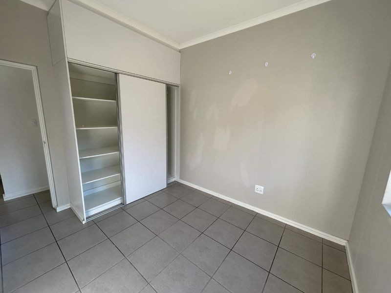An empty bedroom featuring tiled flooring and a built-in sliding door wardrobe, requiring minor cosmetic wall repairs.
