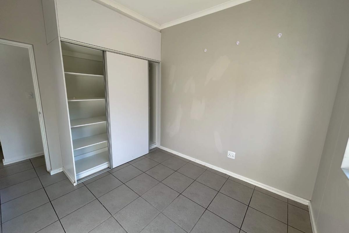 An empty bedroom featuring tiled flooring and a built-in sliding door wardrobe, requiring minor cosmetic wall repairs.